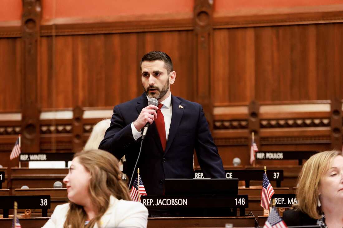 Connecticut state Representative Jonathan Jacobson holds a microphone as he speaks.