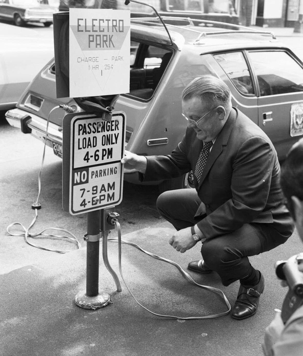 Man kneeling next to a sign that reads Electro Park while charging his car -