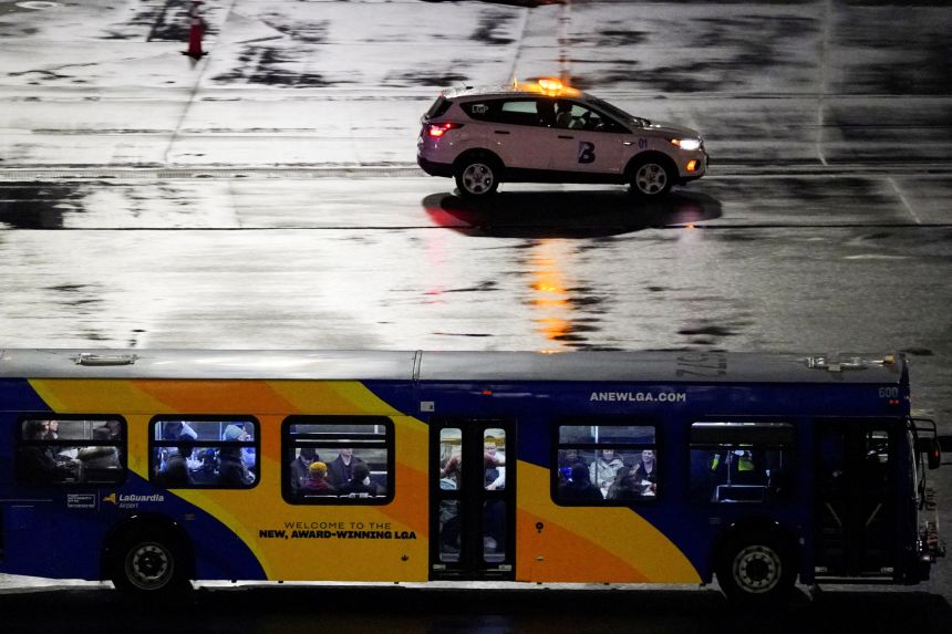 A bus transports passengers from an Air Canada Express jet that collided with a ground vehicle at LaGuardia Airport.