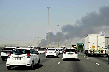 Smoke billows from an ongoing fire near Dubai International Airport as vehicles drive on a highway in Dubai on Monday.