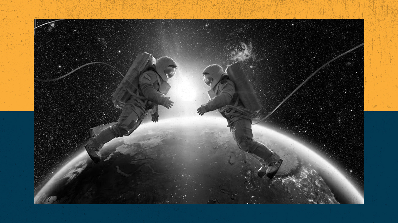 Two astronauts float together in front of Earth.