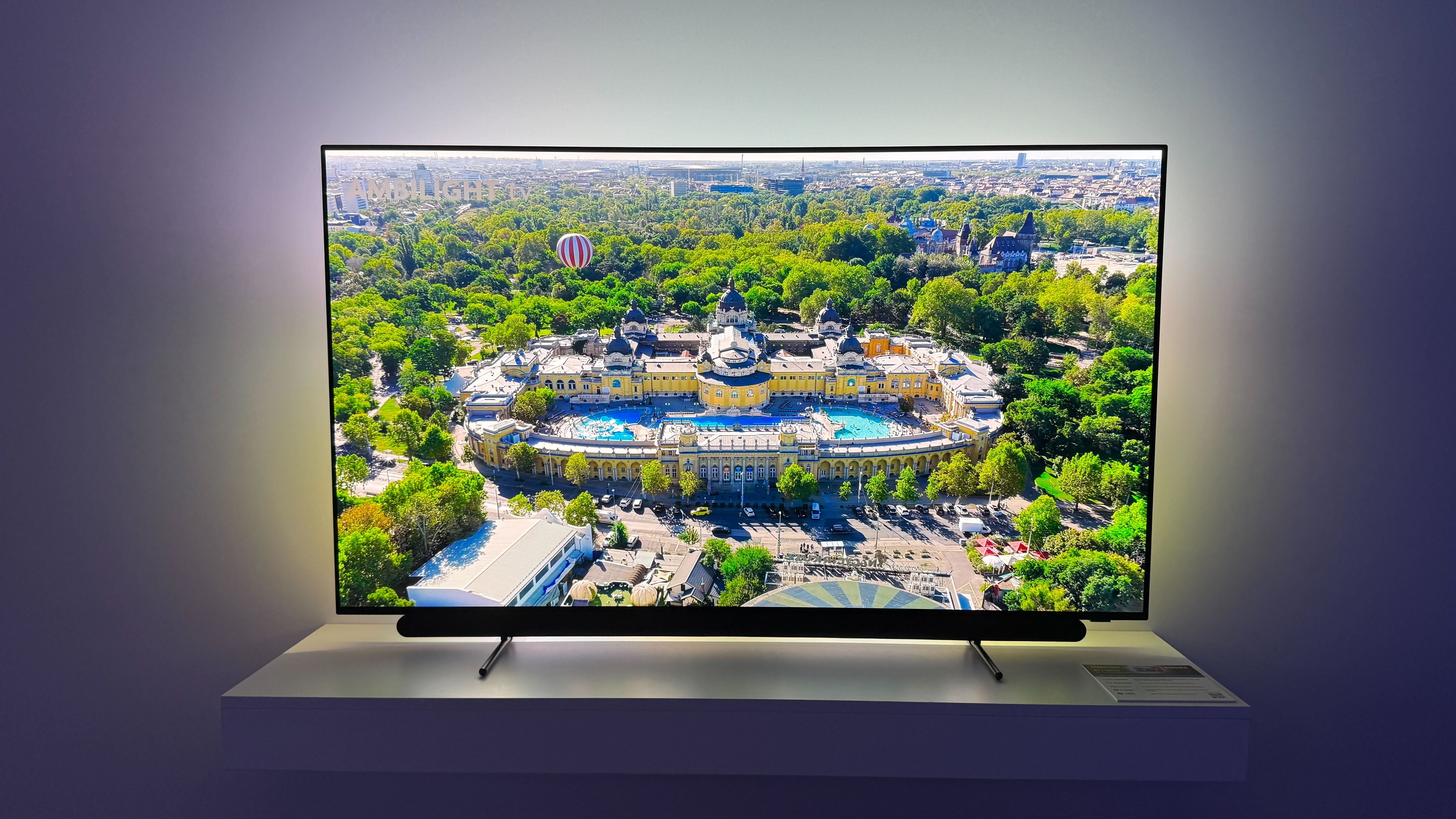 Philips OLED911 on a white shelf with a palace surrounded by trees on screen