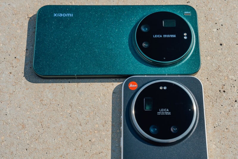 Two smartphones, both with large circular Leica camera modules, are placed on a textured surface. The upper phone is green and labeled "xiaomi," while the lower one is gray.