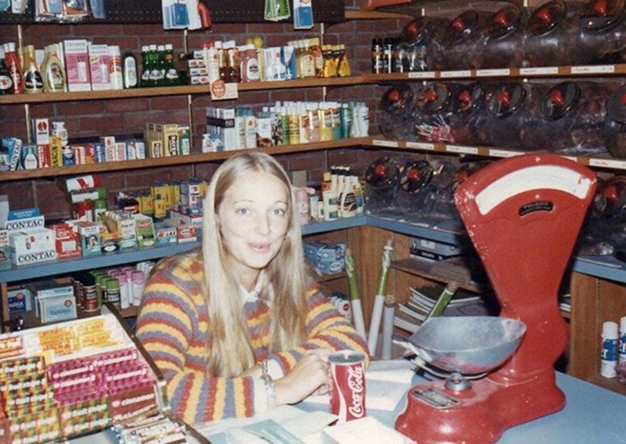 Woman wearing a striped swearing sitting behind the counter at a grocery store -