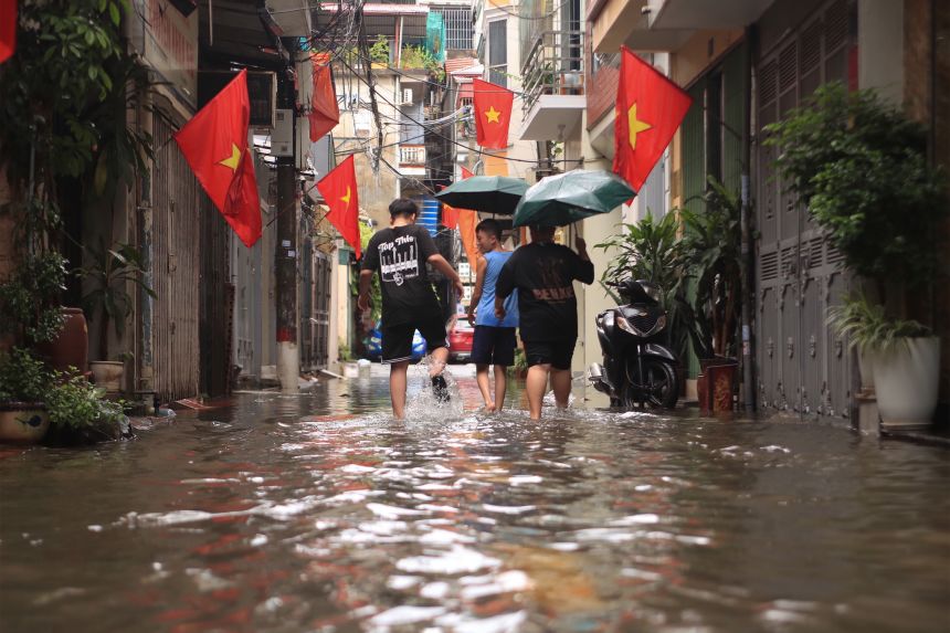 People wade through a flooded alley caused by Typhoon Kajiki in Hanoi, Vietnam, Tuesday, August 26, 2025.