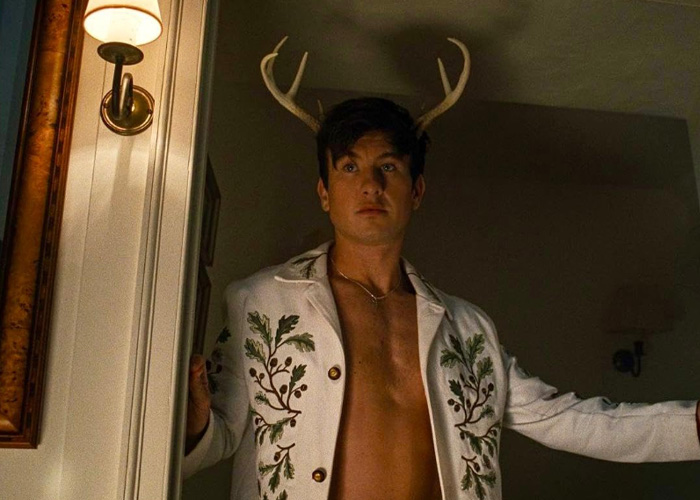Barry Keoghan standing shirtless in decorative jacket with antlers behind him, reflecting on acting career and fan backlash.