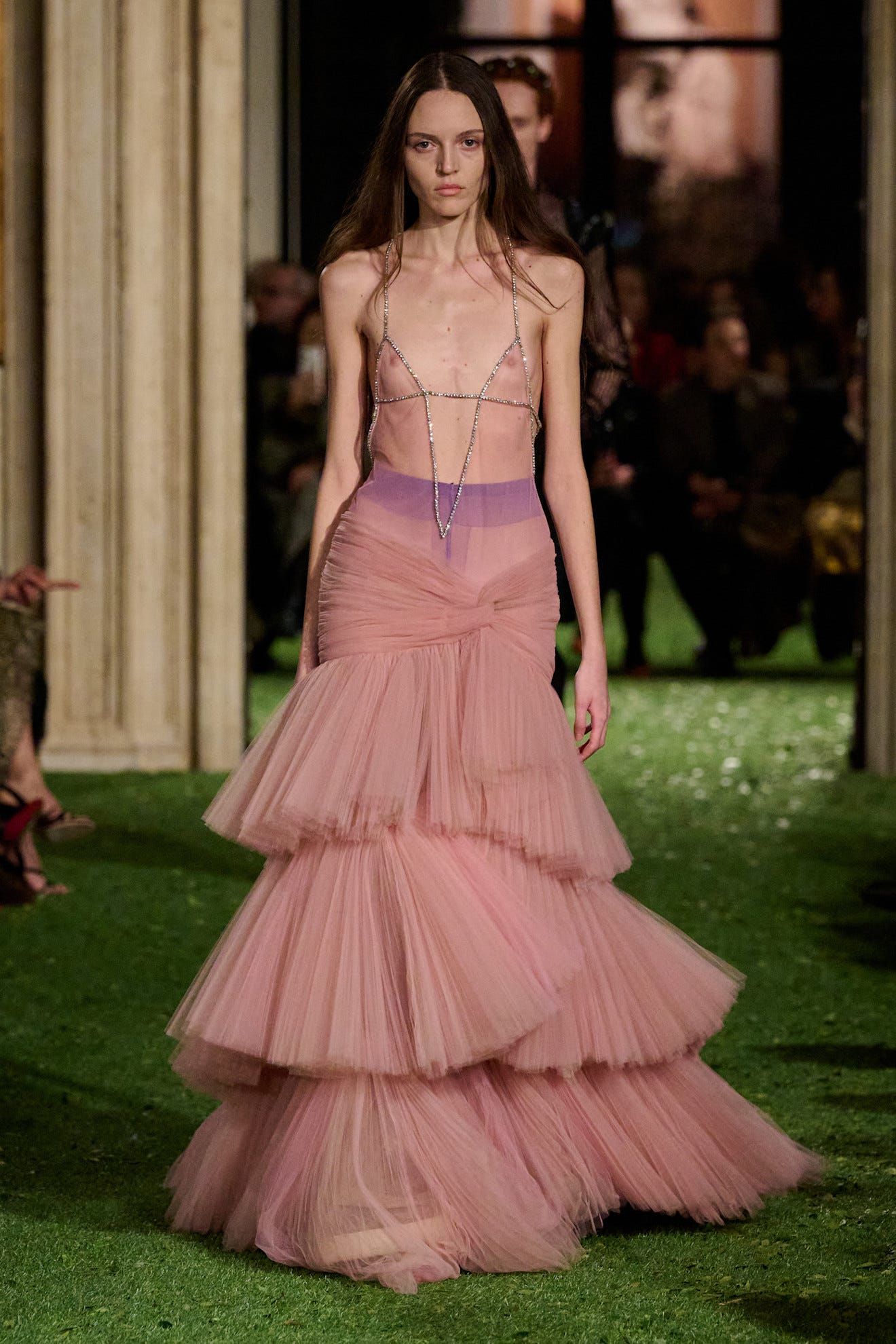 a model showcasing a layered pink gown on a runway