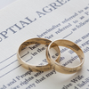 Two overlapping wedding rings sit on top of a prenuptial agreement.