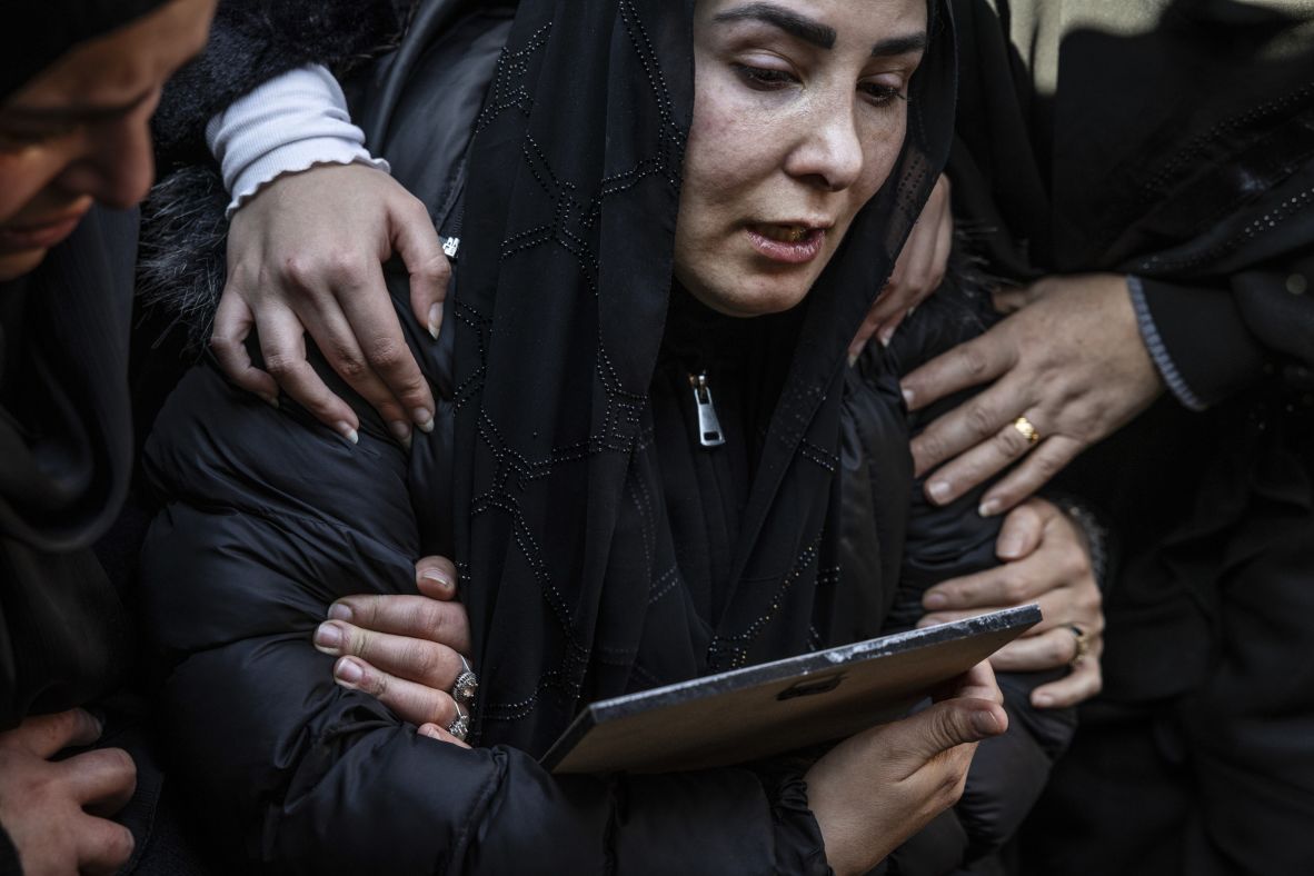 A widow clutches a portrait of her husbnd as his body is placed in a grave at a mass funeral in Nabi Sheet, Lebanon, on Sunday.