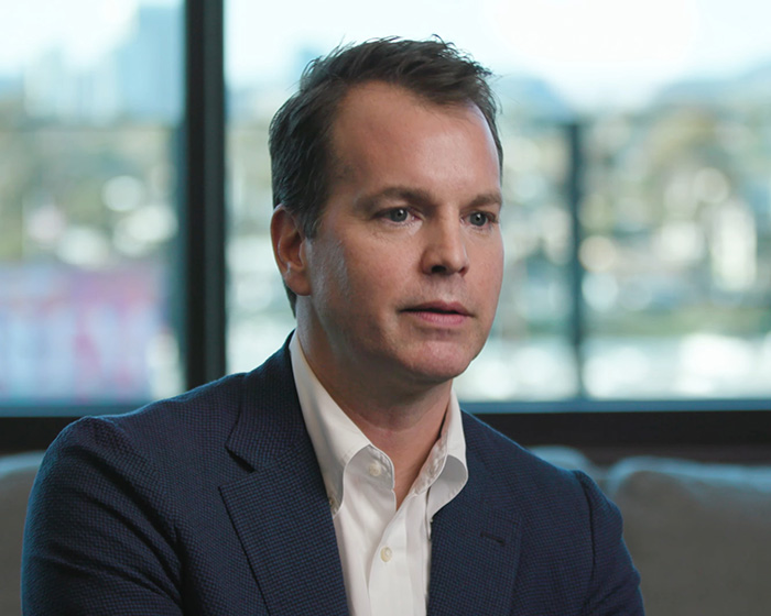 Man in a navy blazer and white shirt indoors near window, representing fans' anger over Harry Potter series race change debate.