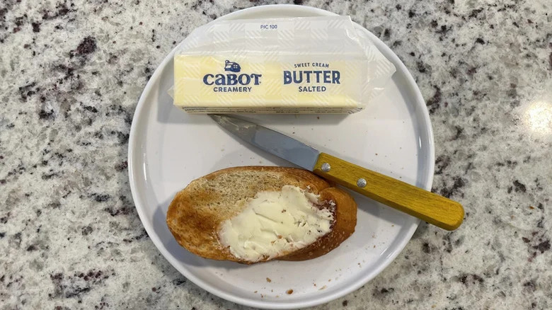 Stick of Cabot salted butter on a plate with a knife and buttered toast