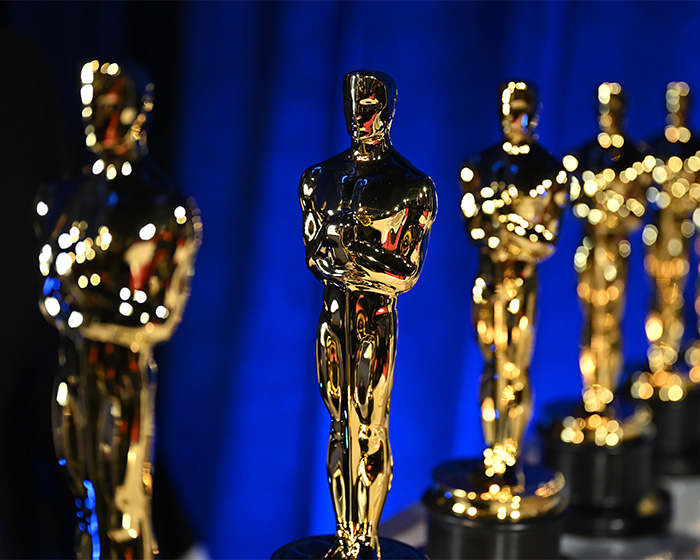 Close-up of multiple shiny Oscars statues against a blue background highlighting the jaw-dropping Oscars gift bag value