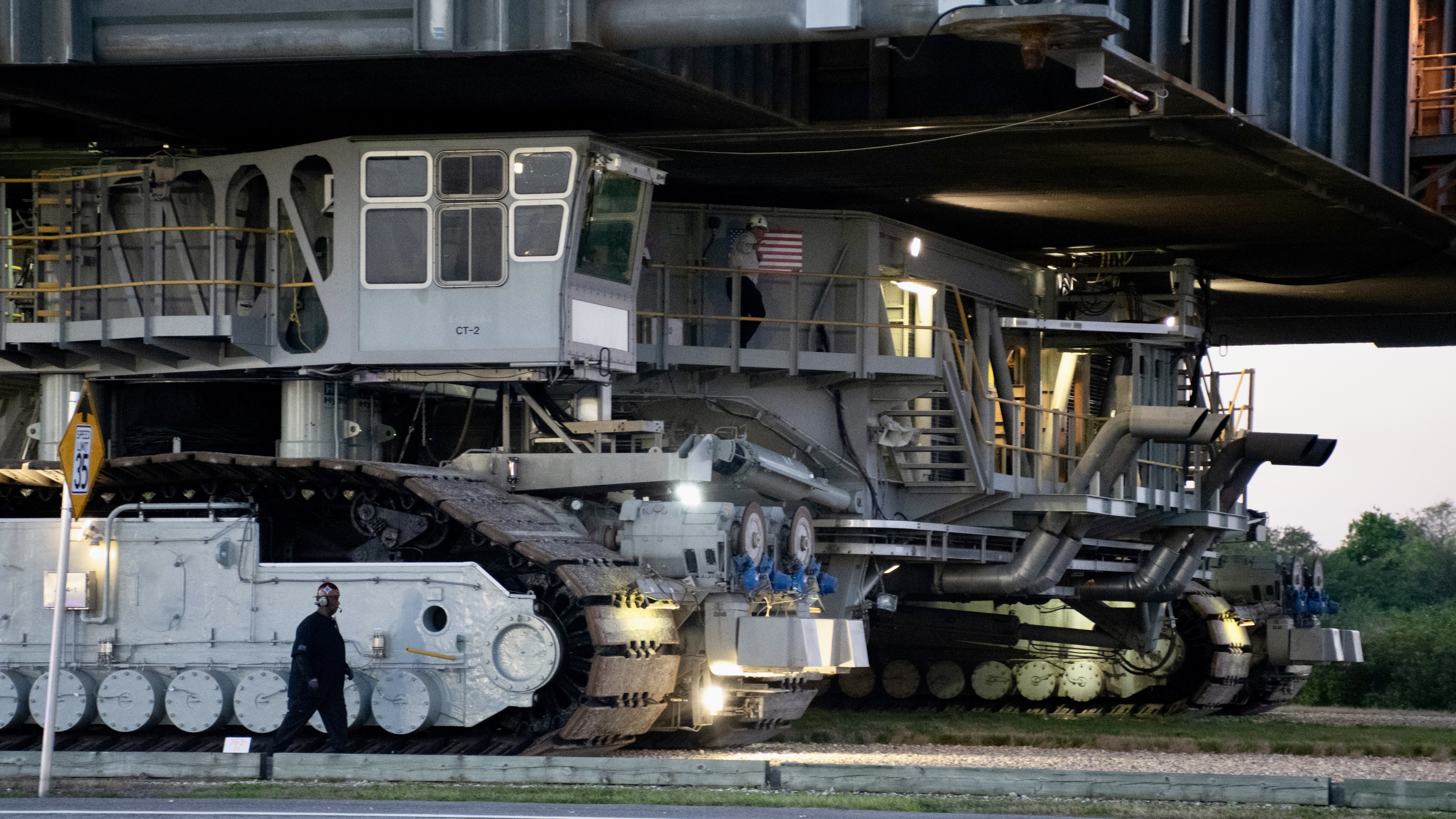 a man walks along the giant treads of a massive ground vehicle.