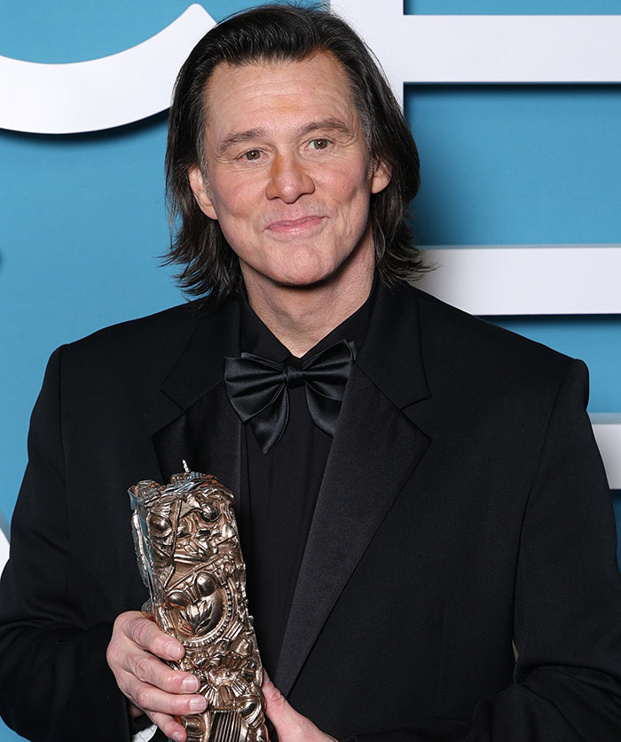 Jim Carrey in a black tuxedo holding an award, with focus on his face after medical verdict controversy. Jim Carrey in a black tuxedo holding an award, with focus on his face after medical verdict controversy.