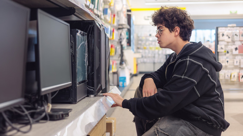 Person examining desktop computers on display in an electronics store