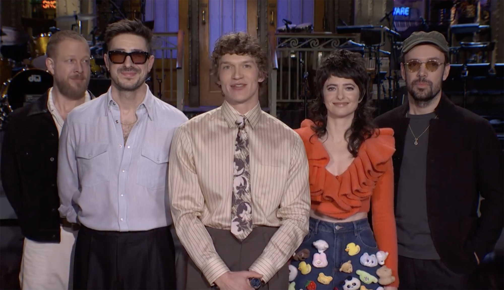 Sarah Squirm, Connor Storrie, and members of Mumford & Sons stand together.