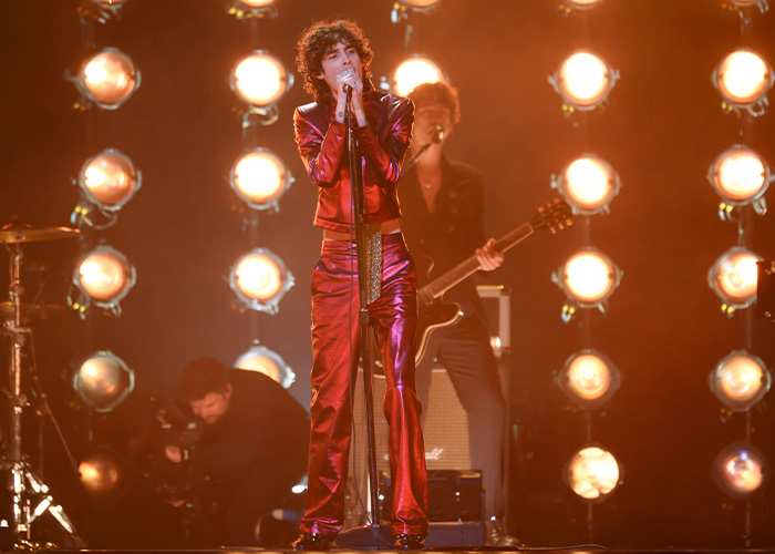 Singer performing on stage amid chaos at Brit Awards with bright lights and musicians in the background during viral moment. Singer performing on stage amid chaos at Brit Awards with bright lights and musicians in the background during viral moment.