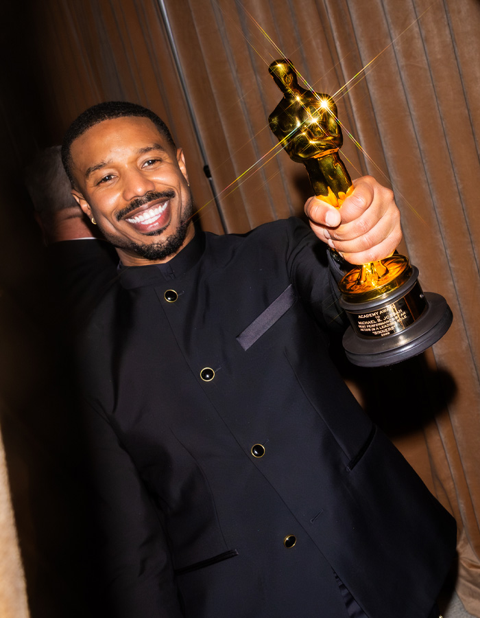 Michael B Jordan smiling and holding an Oscar trophy after the Oscars, attention-raising moment captured.