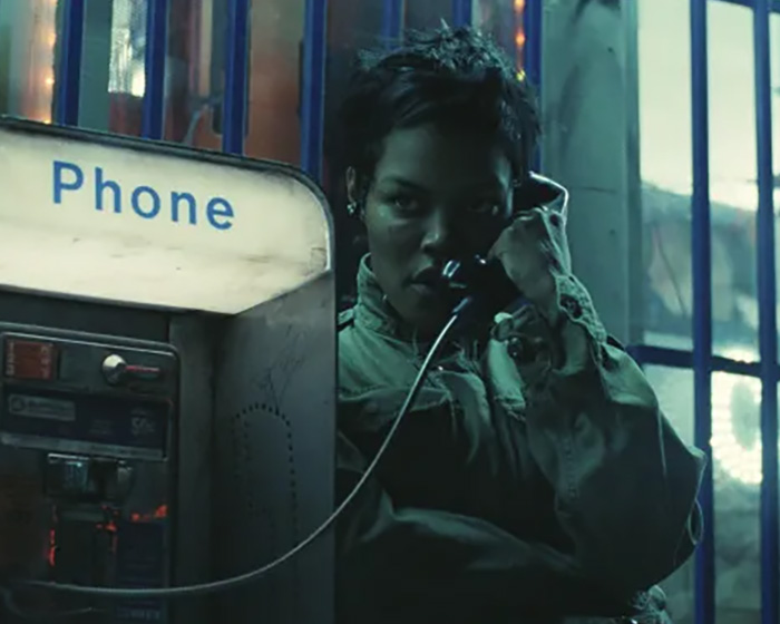 Teyana Taylor using a payphone in a dimly lit urban setting during a viral Oscars moment with security guard.