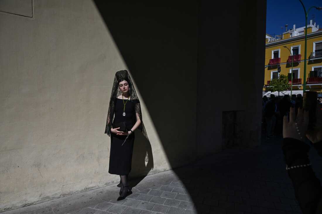 A woman wearing a traditional shawl known as a "mantilla" stands outside the Basilica de la Macarena church during Holy Week in Seville on April 2, 2026. 
