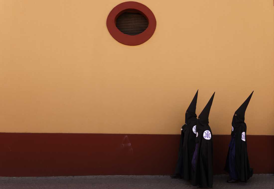 Penitents of San Bernardo brotherhood walk to their church before taking part in a procession during Holy Week