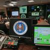 A monitor at a computer workstation bears the National Security Agency logo inside the Threat Operations Center.