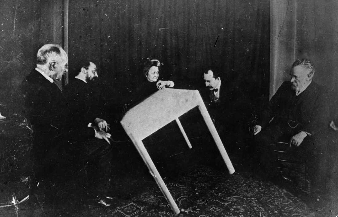 A table appears to move of its own accord during a seance in Paris in 1900.