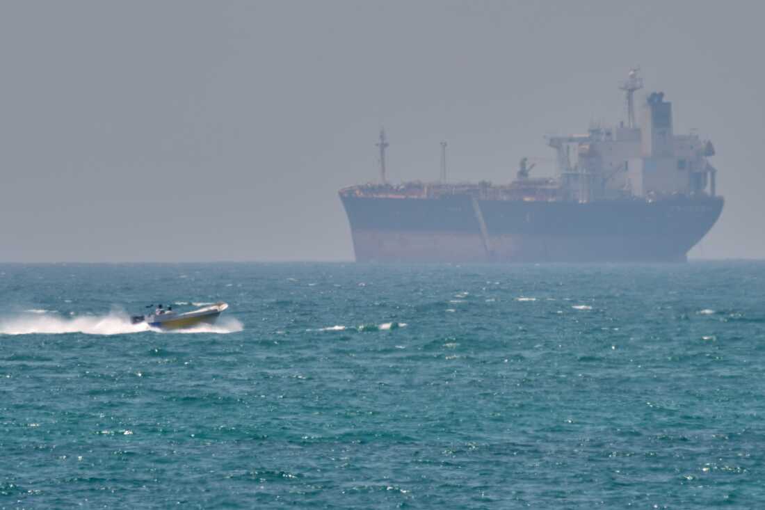 A boat sails past a tanker anchored on the Strait of Hormuz off the coast Qeshm island, Iran, April 18.