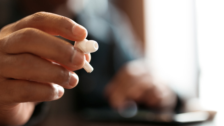 A hand holding AirPods.